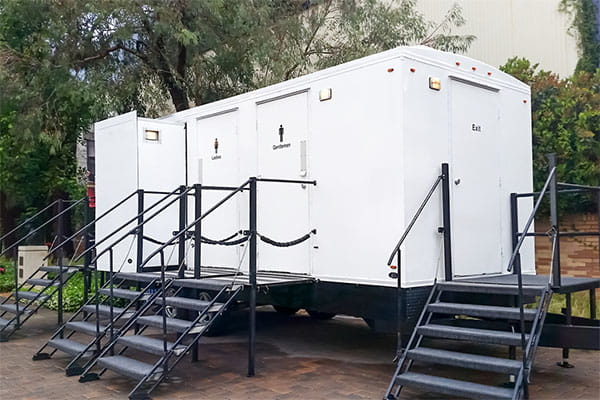 porta potty rental company staff performing maintenance on restroom trailer plumbing