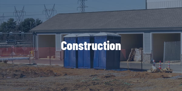 blue portable toilets at residential home construction area with workers in safety vests